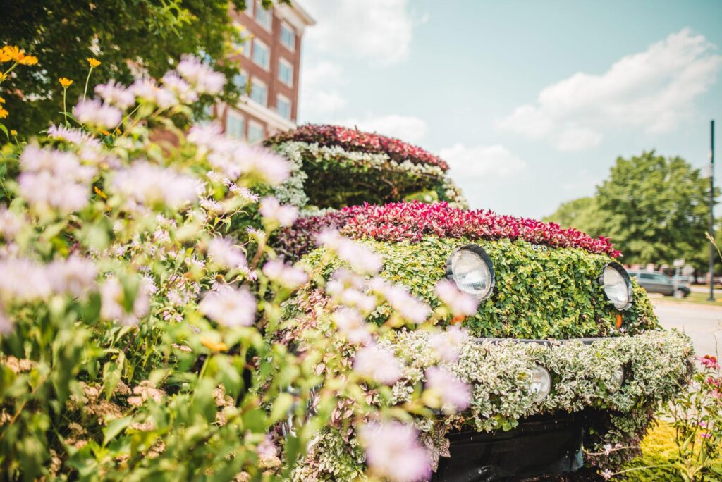 A topiary of a life-sized Jeep with flowers in the foreground.